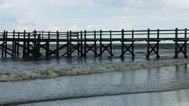 Wooden bridge over the North Sea to a stilt house on the beach of St. Peter Ording, slow motion