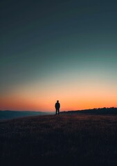 Obraz na płótnie Canvas Man standing alone on a hill during sunset