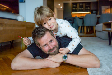 Portrait of happy smiling young father and little son lying on floor at home. Concept of single...