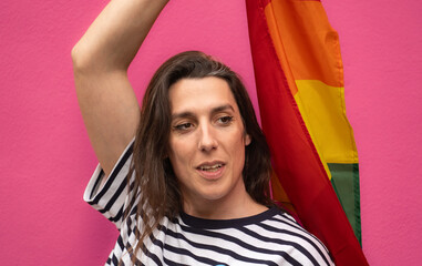 Headshot of a happy transgender woman holding a rainbow flag isolated on pin background