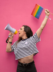 Portrait of transgender woman shouting with a megaphone and holding a rainbow flag supporting LGBTQ+ community
