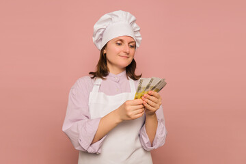 Woman cook with euro money on studio pink background. Portrait of a female person in chef's clothing
