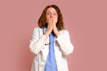Scared female doctor, studio pink background. Nurse in uniform with stethoscope on red studio...