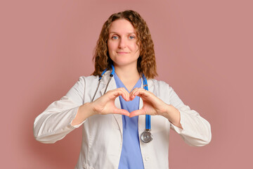 Woman doctor heart gesture, studio pink background. Nurse in uniform with stethoscope on red studio background