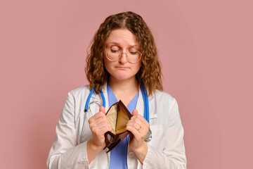Woman doctor holding an empty wallet in her hands, studio pink background. Nurse in uniform with stethoscope on red studio background