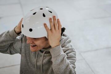 Man taking off white skate helmet, sports safety equipment