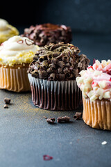 Close up of some decadent gourmet cupcakes frosted with a variety of frosting flavors.