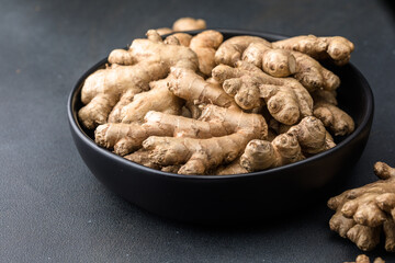 Ginger roots from the garden in plate on black surface