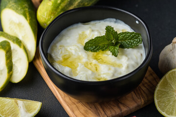 A bowl of tzatziki dip and fresh cut vegetable sticks next to it