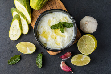 A bowl of tzatziki dip and fresh cut vegetable sticks next to it