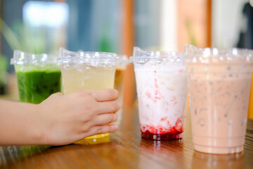 Woman hand hold plastic cup a lot of sweet or coffee on the wooden table background in cafe restaurant, celebrate,party, meeting