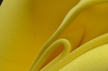 folds of yellow foam sponge. bright yellow material. rolled in a spiral shape - obrazy, fototapety, plakaty