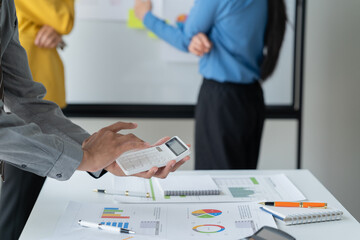 close-up hands image, Professional Asian male and female financial consultant or analyst working with them team, brainstorming and analyzing financial data on the report together in the office