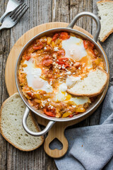Shakshuka with eggs tomato and parsley in a cast iron pan.