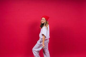 Kid girl doing fitness exercises with dumbbells on red background