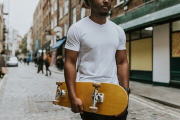 Man in white tee walking in town with wooden skateboard © Rawpixel.com