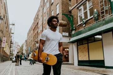 Man walking in town with wooden skateboard © Rawpixel.com
