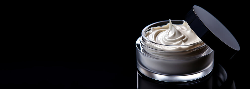 White face and body cream in a glass jar stands on a dark table. Concept of skincare cosmetics for face and body, self-care, banner with copyspace