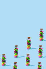 A pattern of glass bottles full of colorful candies on a blue background with copy space.