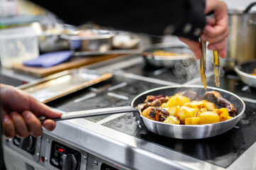 A skilled chef expertly cooks diced potatoes and meat in a sizzling frying pan, showcasing culinary artistry