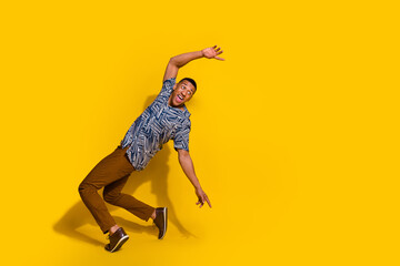 Full length photo of attractive funny guy wear print shirt dancing emtpy space isolated yellow...