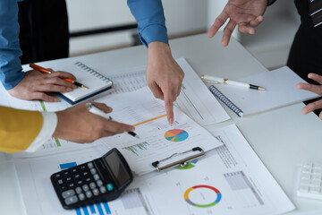 close-up hands image, Professional Asian male and female financial consultant or analyst working with them team, brainstorming and analyzing financial data on the report together in the office