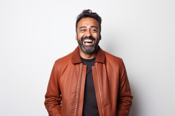 Obraz premium Portrait of a cheerful indian man in his 40s wearing a trendy bomber jacket over white background