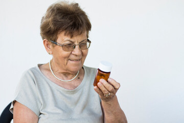 Mature woman in glasses hold bottle with pills read medicine instruction on packaging before take...