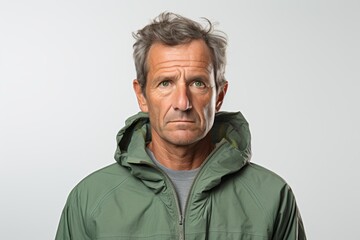 Obraz premium Portrait of a tender man in his 50s wearing a functional windbreaker over white background