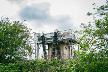 View of the tall concrete sewage water treatment effluent extraction facility. The extracted sludge is removed down the back tubing to a waiting tanker truck.