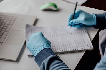 professional working with numerical data. Clad in blue gloves, person carefully logs information, highlighting precision necessary in scientific or clinical data analysis - Powered by Adobe