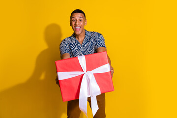 Photo of attractive funny guy wear print shirt getting new year present isolated yellow color background