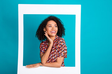 Photo of positive girl in photo frame look empty space isolated cyan color background