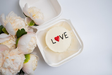 Bento cake with the inscription "Love and Hearts" and a bouquet of flowers. A cute dessert gift for any occasion for a loved one. Greeting card. Love and sweets concept