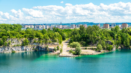 View of Lake Zakrzówek with apartment buildings in the background. Locals swimming in the crystal...