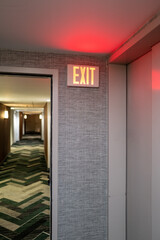 Red Lit Exit Sign in Hotel Corridor