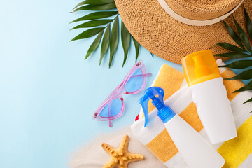 Top view of summer beach essentials including a straw hat, sunscreen, and beach towel, ideal for...