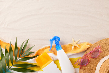 Arranged beach scene featuring sun protection sprays, a straw hat, and sunglasses, capturing the...