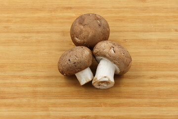 Fresh champignon mushroom isolated on wooden background