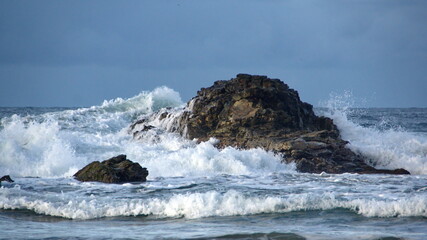 Obraz premium Waves breaking over rocks just off the beach in Zipolite, Mexico