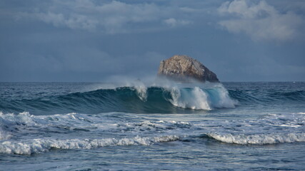 Fototapeta premium Waves in front of an islet just off the beach in Zipolite, Mexico