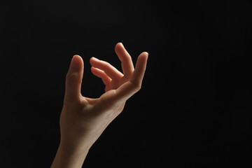 Woman holding something in hand on black background, closeup. Space for text