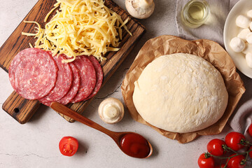 Pizza dough and products on gray textured table, flat lay