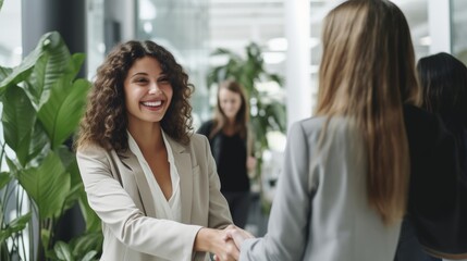 Fototapeta premium In an office meeting, confident young Hispanic businesswoman shakes hands with coworker. Happy woman celebrating a promotion, transaction, and merger. Creative startup agency coworkers