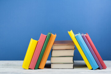 Book stacking. Open book, hardback books on wooden table and blue background. Back to school. Copy...