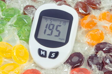 Glucometer with high sugar level and candies. Healthy lifestyle, nutrition and reduction eating sweets during diabetes