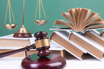 Law concept - Open law book, Judge's gavel, scales, on table in a courtroom or law enforcement...