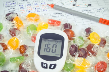 Glucose meter with high sugar level, candies and medical form. Measuring and checking sugar level