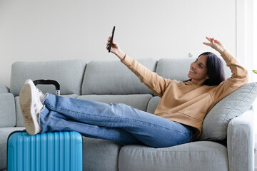happy woman lying on the couch taking a selfie waiting to go on summer vacation