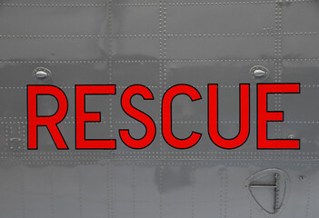 The word Rescue written in red capital letters on the metal fuselage of an old helicopter